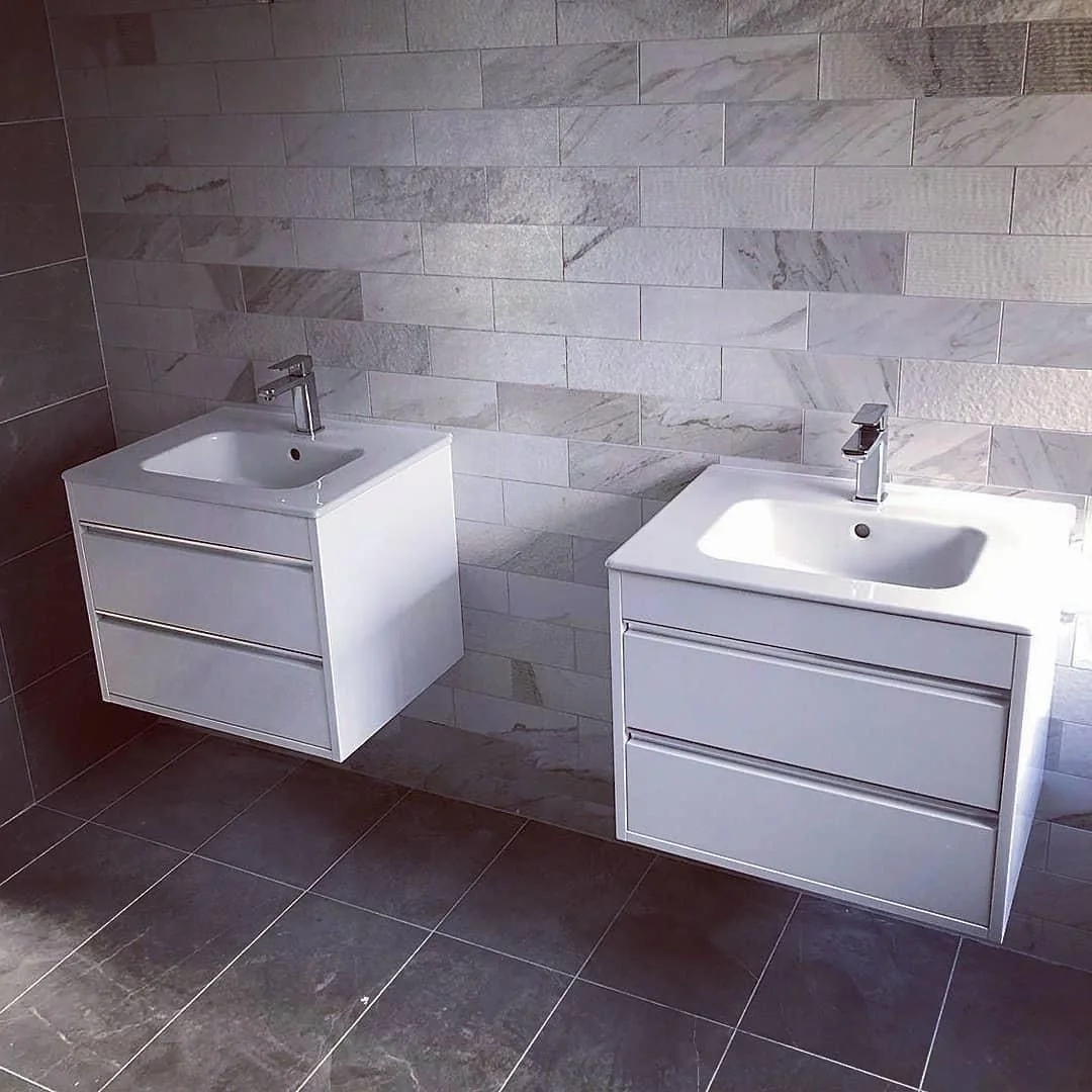 Wall hung vanity units with basins and chrome mixer taps, fitted against marble effect tiling by Heritage Heating Services