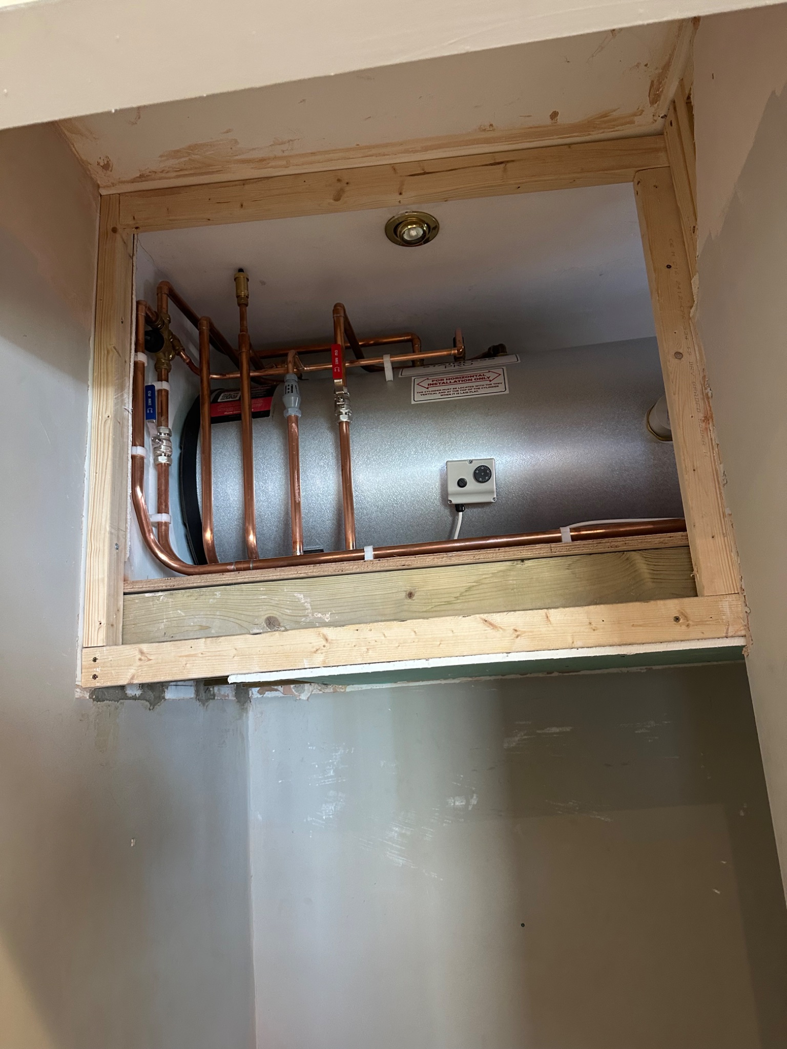 Horizontal unvented cylinder installed in a purpose built cubby above a stairwell in Bath