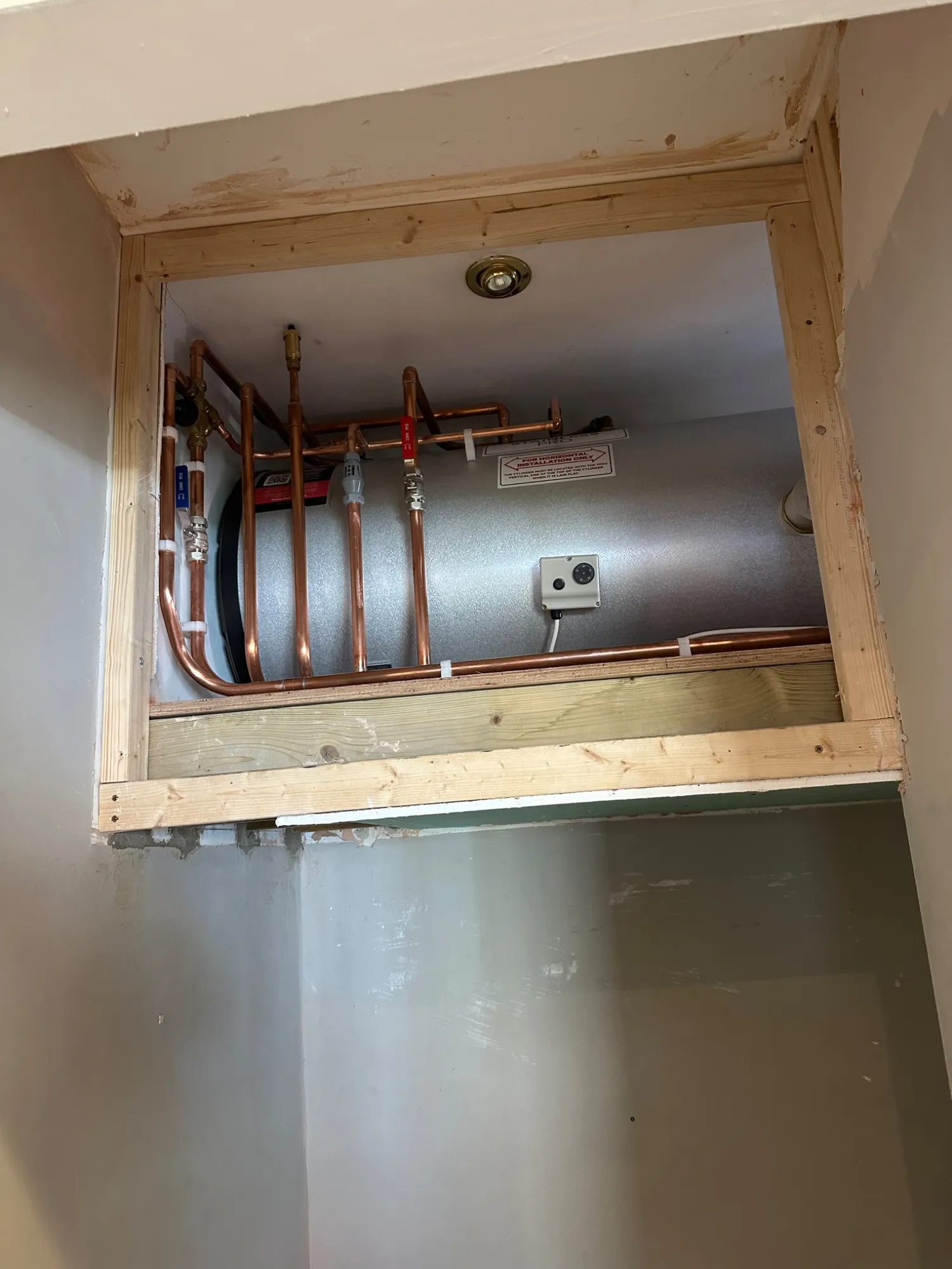 Horizontal unvented cylinder installed in a purpose-built cubby above a stairwell in Bath